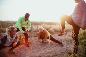 People stretching on a rocky shore on a sunny morning