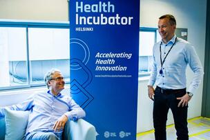 Two men next to the Health Incubator Helsinki roll-up.