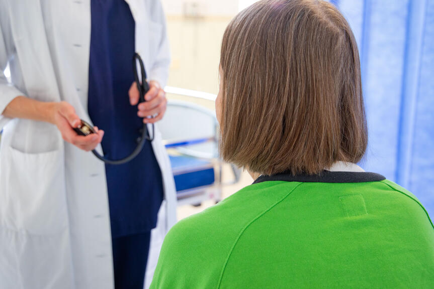 In the foreground, a client; in the background, a doctor with a stethoscope.