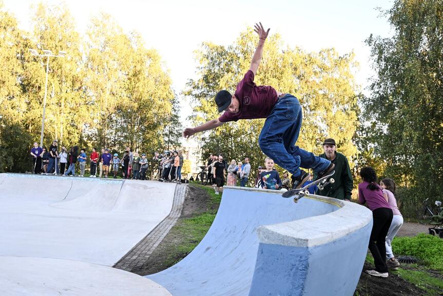 A young man skating. There are other young people around watching.