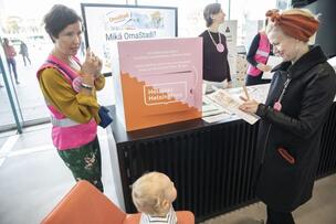 Ihmiset kohtaavat keskustellen OmaStadin merkeissä Helsingin keskustakirjasto Oodissa vuonna 2019.