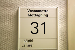 Seinällä oleva kyltti, jossa teksti "Vastaanotto Lääkäri". 