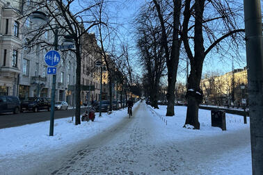 Talvinen katunäkymä ja pyöräilijä.