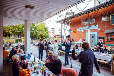 Bändi esiintymässä ja ihmisiä kuuntelemassa Malminkartanon yhteisöllisellä illallisella.