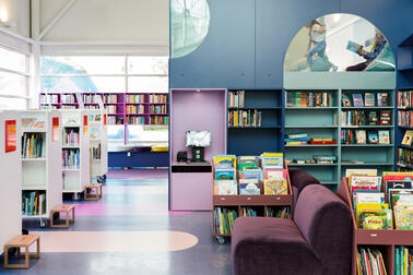 Blue-toned bookshelves and a reading loft in Pikku Huopalahti Library's main hall.