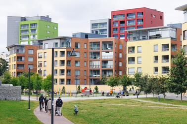 Perhe ulkoilemassa puistossa, taustalla näkyy kerrostaloja.