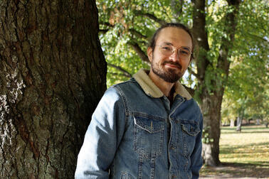 Topi, the father of the foster family, leans against a tree.