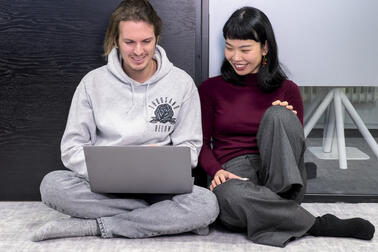 kaksi henkilöä katsomassa kannettavan tietokoneen näyttöä