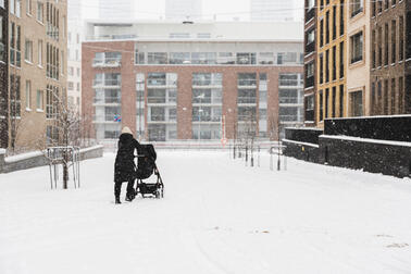 Nainen lumessa lastenrattaiden kanssa