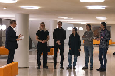 Jolkkonen puhuu viidelle palkittavalle ohjelmistosuunnittelijalle tyylikkäässä aulassa. 