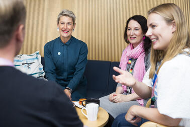 Fyra personer diskuterar vid kaffebordet.