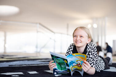 Lapsi lukee lattialla Aku Ankkaa.