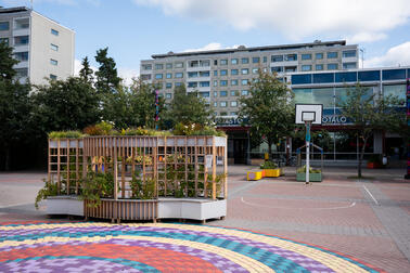 A view from the square towards a low office building, with an apartment building behind it.