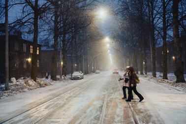 Kaksi ihmistä ylittää katua talvisessa Käpylässä.