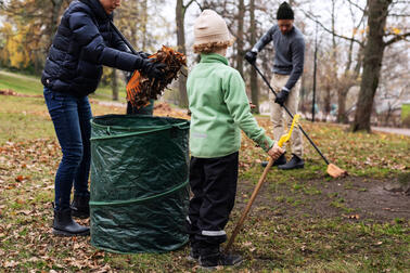 Ett barn och en familj krattar i Brunnsparken.