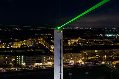 Ajan Lennätin lähettää lasersäteitä Olympiastadionin tornista.