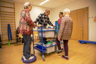 Neljä henkilöä seisoo liikuntasalissa ympyrässä.