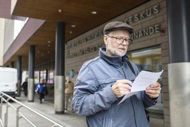 Mies lukee kädessään olevaa paperia.