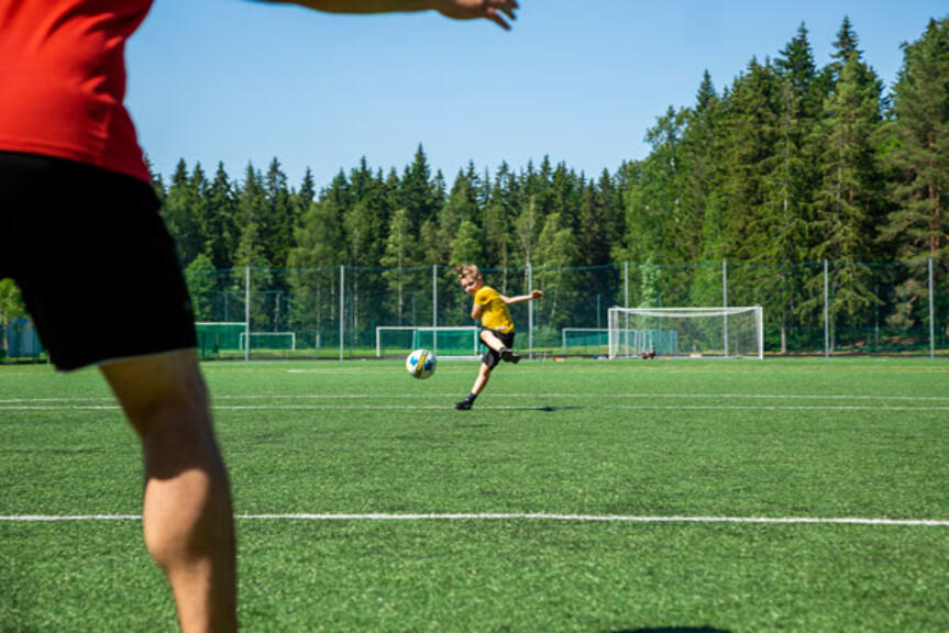 Kaksi jalkapallon pelaajaa tekonurmikentällä.