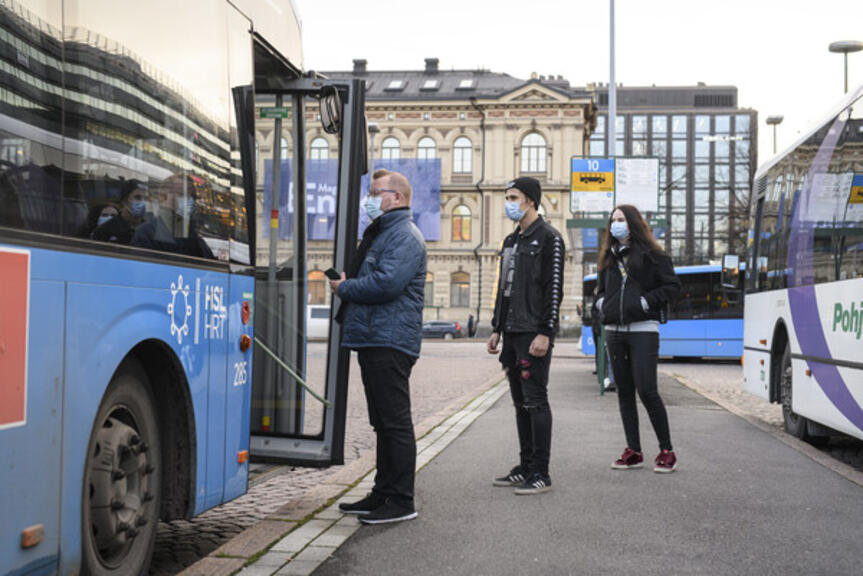 Ihmisiä jonottamassa bussiin maskit päällä. Ihmisiä jonottamassa bussiin maskit päällä.