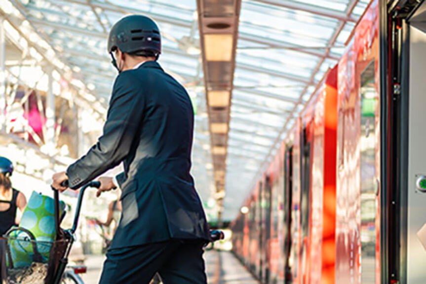 Kypäräpäinen mies astuu ulos metrojunasta potkulaudan kanssa. Kypäräpäinen mies astuu ulos metrojunasta potkulaudan kanssa.