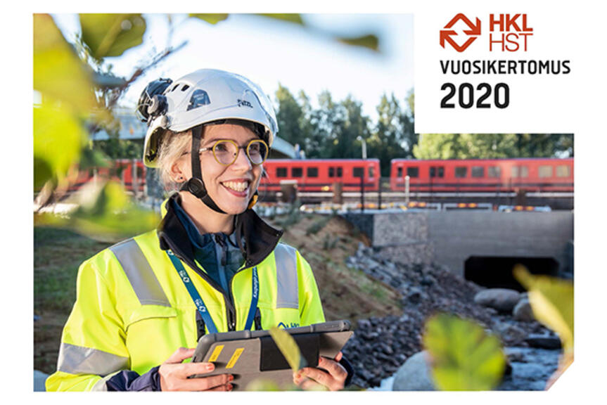 Vuosikertomuksen kannessa nainen kypärä päässä hymyilee, taustalla kulkee metro. Vuosikertomuksen kannessa nainen kypärä päässä hymyilee, taustalla kulkee metro.
