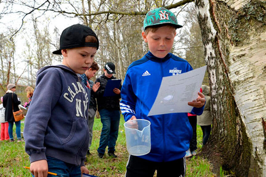 Kaksi koululaista ympäristökasvatuksen tunnilla ulkona. Kaksi koululaista ympäristökasvatuksen tunnilla ulkona.