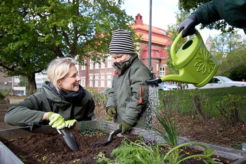 Aikuinen ja lapsi kasvipenkin juurella. Aikuinen ja lapsi kasvipenkin juurella.