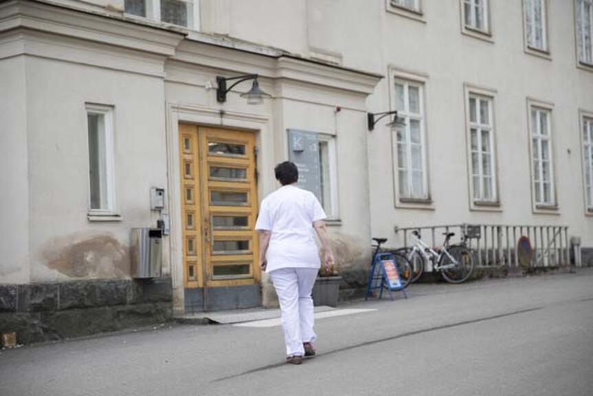 Hoitaja kävelee kohti sairaalan ulko-ovea.