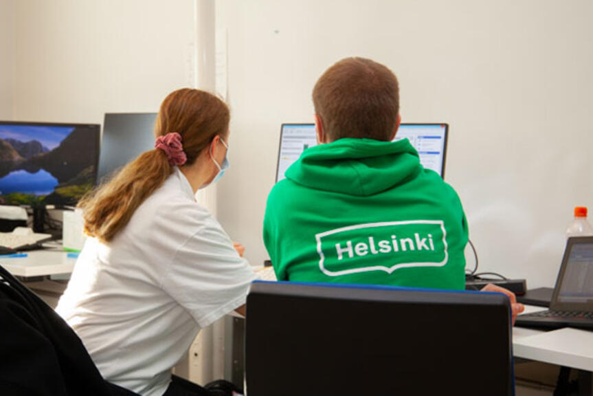 Kaksi kotihoidon työntekijää tietokoneen ääressä. Kaksi kotihoidon työntekijää tietokoneen ääressä.