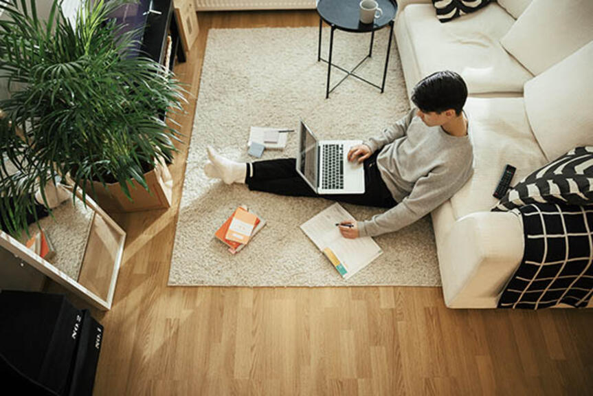 Mies selaa nettiä läppärillään olohuoneen lattialla. Mies selaa nettiä läppärillään olohuoneen lattialla.