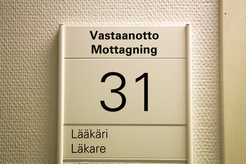 Seinällä oleva kyltti, jossa teksti "Vastaanotto Lääkäri". Seinällä oleva kyltti, jossa teksti "Vastaanotto Lääkäri".