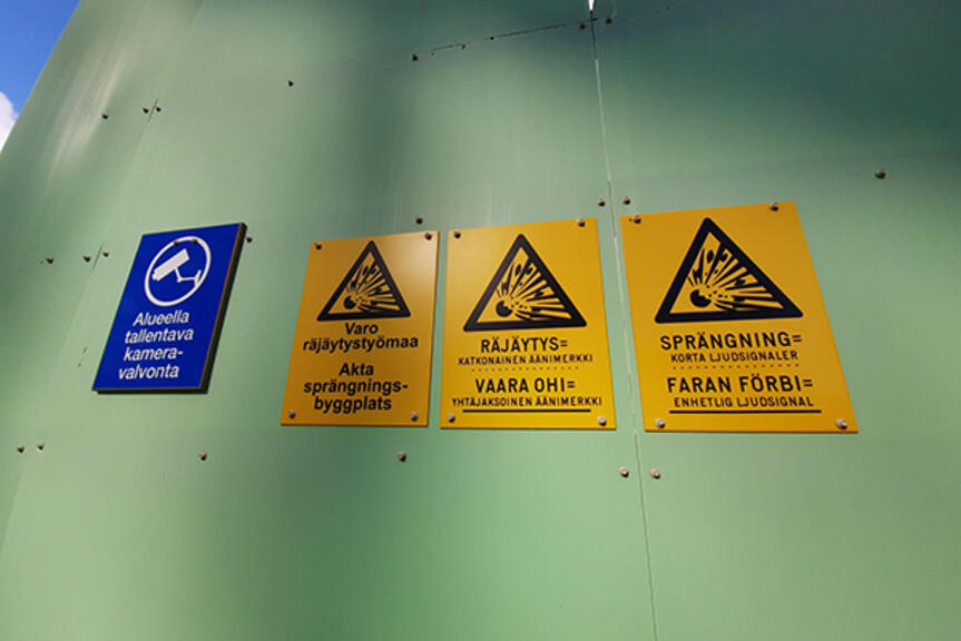 Räjäytysten varoitusmerkkejä työmaa-aidassa. Räjäytysten varoitusmerkkejä työmaa-aidassa.