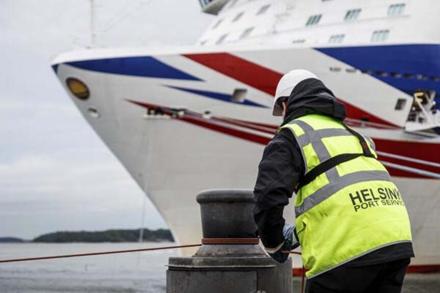 Helsingin sataman työntekijä kiinnittämässä risteilyaluksen köyttä. Helsingin sataman työntekijä kiinnittämässä risteilyaluksen köyttä.