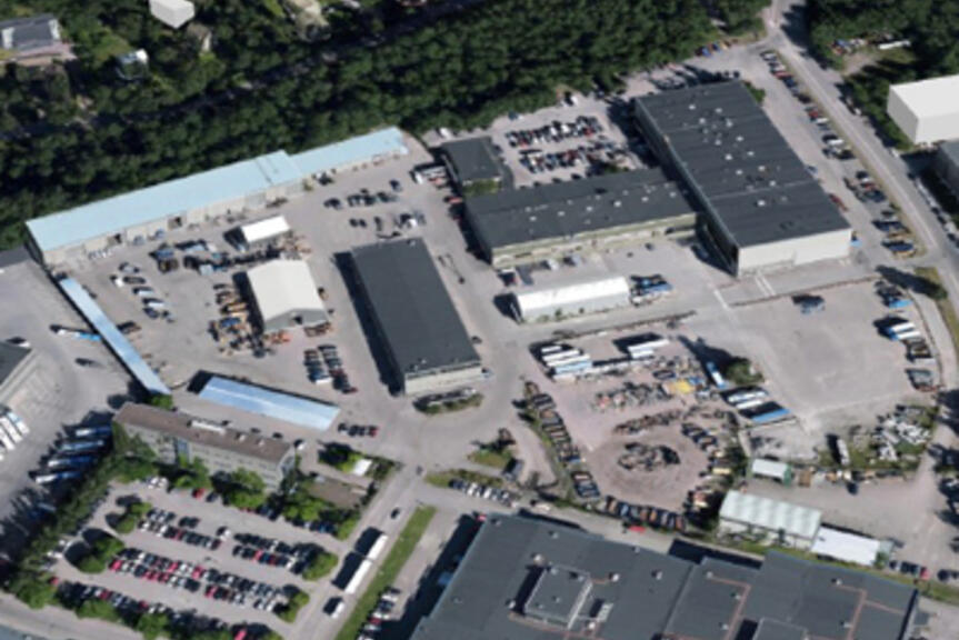 Yksi- ja kaksikerroksisia teollisuusrakennuksia parkkipaikan keskellä. Yksi- ja kaksikerroksisia teollisuusrakennuksia parkkipaikan keskellä.