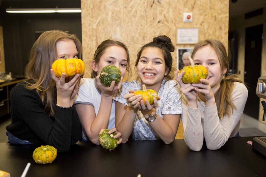 Kuvassa neljä iloista tyttöä kurpitsat kädessä. Harrastamisen Suomen malli tarjoaa myös kokkausharrastuksia.