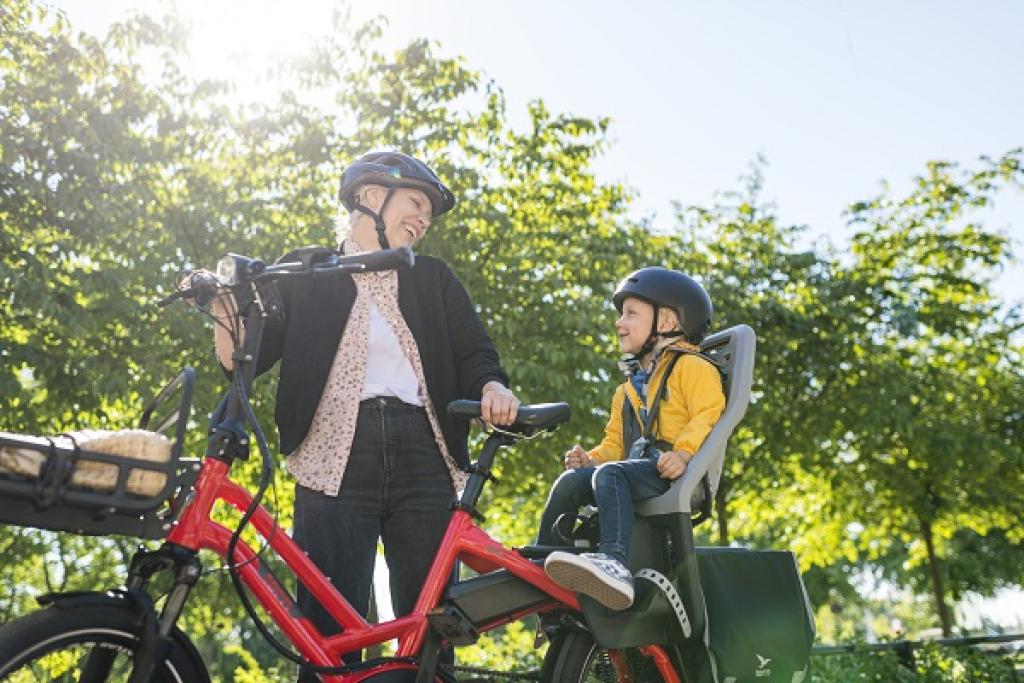 Äiti ja lapsi nauttivat pyöräilystä puistossa.