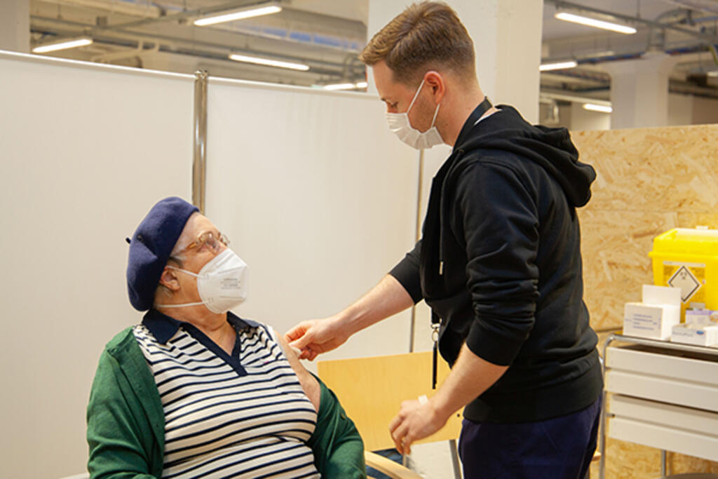 Asiakas ja hoitaja juttelevat rokotuspisteellä. Asiakas ja hoitaja juttelevat rokotuspisteellä.