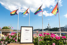 Helsingin kaupungin Ylpeys muuttaa maailmaa -tunnustuspalkinto kaupungintalon parvekkeella Pride-lippujen edessä.