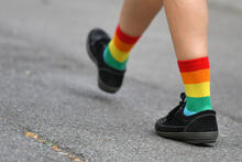 Lähikuva kävelijän jaloista, joihin puettu sateenkaaren väreissä olevat sukat.