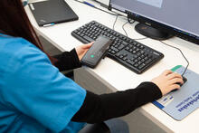 Terveydenhoitaja työpisteellään puhelimen ja tietokoneen ääressä. 