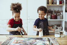 Kuvassa kaksi lasta maalaavat taidetyöpajassa.