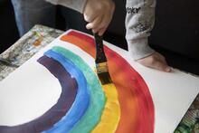 Lapsi maalaa vesiväreillä sateenkaarta