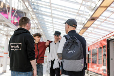 Neljä nuorta seisoo metroasemalla juttelemassa.