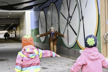 Kaksi pientä lasta on juoksemassa naisen syliin.