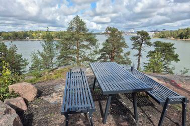 Pöytä ja tuolit kallioisessa metsämaisemassa.