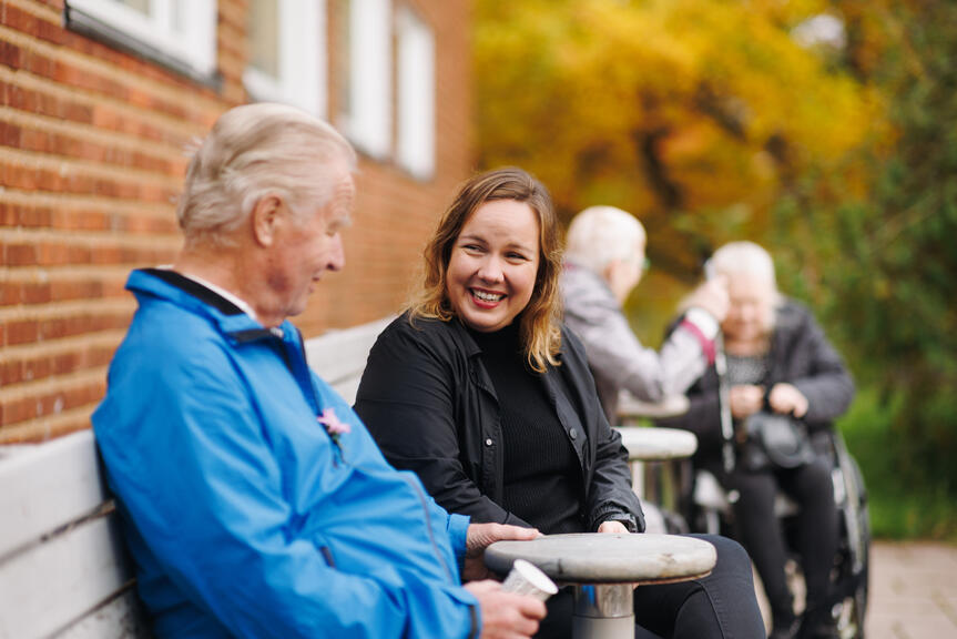 Ihmiset istuvat pihalla ja keskustelevat.