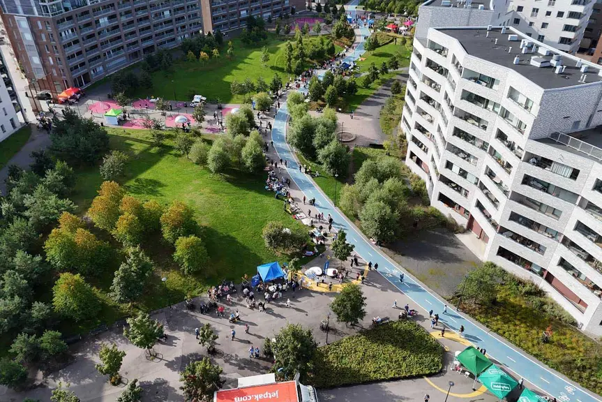 Ilmakuva Hyväntoivonpuistosta, jossa tapahtumavieraita, toimintapisteitä ja viheralueita asuinrakennusten keskellä.