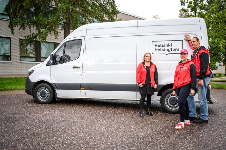 Kolme työntekjiää katsoo kameraan, heidän takanaan pakettiauto sivuittain.