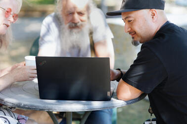Kolme henkilöä tietokoneen ääressä.